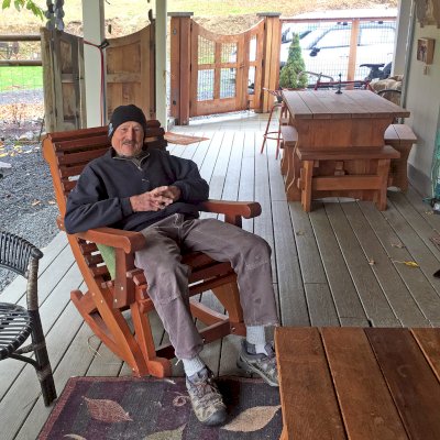 Ensenada Wooden Rocking Chair (Options: Standard Width, Old-Growth Redwood, No Cushion,Transparent Premium Sealant). Photo also shows a Trestle Table Set in background. Photo Courtesy of R. Bogardus of Jacksonville, OR.