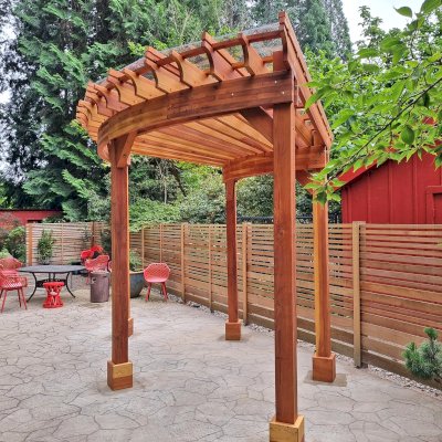 Fan Shaped Pergola Kit (Options: 15' x 18', California Redwood, Open Roof Slats at 12in, With Transparent Rain Guard, Electrical Wiring Trim Kit for 1 Post, Post Anchor Kit for Concrete, No Ceiling Fan Base, 10' Posts, No Curtain Rods, Transparent Premium Sealant). Photo Courtesy of G. Fish of Vancouver, WA.