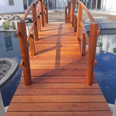 Custom Forever Foot Bridge (Options: 21' L, Mature Redwood, 5' Wide Instead of the Standard 4' Width, Arched 2x4 Handrail and Circular 6x6 Posts on Corners and Center by Custom Request, Transparent Premium Sealant). Photo Courtesy of Hino Medical Center of Ensenada, Baja California, Mexico.