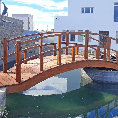 Custom Forever Foot Bridge (Options: 21' L, Mature Redwood, 5' Wide Instead of the Standard 4' Width, Arched 2x4 Handrail and Circular 6x6 Posts on Corners and Center by Custom Request, Transparent Premium Sealant). Photo Courtesy of Hino Medical Center of Ensenada, Baja California, Mexico.