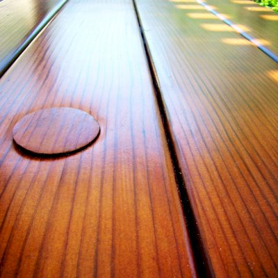 Closeup of tabletop highlighting the quality of the vertical grain lumber and the Transparent Premium Sealant - Mature Redwood. Umbrella hole and plug is shown on top left.
