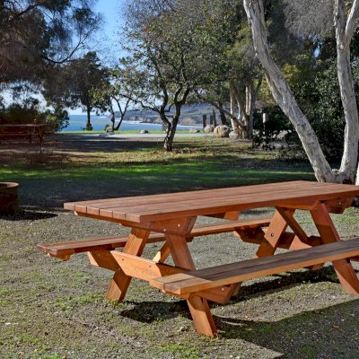 Forever Picnic Tables (Attached Benches) (Options: 8' L, 34 1/2" W, Side Benches, California Redwood, Standard Tabletop, Squared Corners, No Umbrella Hole, Transparent Premium Sealant). Located at El Capitan State Beach near Santa Barbara, CA part of a 90 table installation completed in 2015.