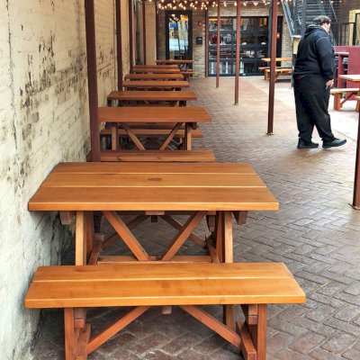 Forever Picnic Tables (Unattached Benches) (Options: 4', 34 ½in W, Side Benches, Mature Redwood, 1 Full Length Side Bench Per Side, Standard Tabletop, Squared Corners, 2in Umbrella Hole, Transparent Premium Sealant). Standard design is with 5 3/4" wide boards. The tabletops in this photo were built for the restaurant by request using bookend construction (where 2 standard width 5 3/4" wide boards are tongue and grooved together to appear as one wider 11 1/2" wide board). If you would like this effect for your tables, just add a note saying want bookend detail added to your order (no extra charge to do this). Photo courtesy of M. Piekarz of Chicago, IL.