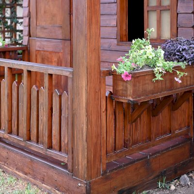 Kid's Backyard Cabin (Options: 12ft L x 8ft W, 7ft Wall H, Douglas-Fir, 4ft Front Porch Size [Included in the Overall Length], Interior Decking, Transparent Premium Sealant). Photo shows structure recently resealed after 6 years of loving service.