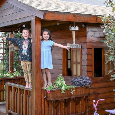 Kid's Backyard Cabin (Options: 12ft L x 8ft W, 7ft Wall H, Douglas-Fir, 4ft Front Porch Size [Included in the Overall Length], Interior Decking, Transparent Premium Sealant). Photo shows structure recently resealed after 6 years of loving service.