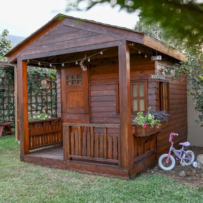 Kid's Backyard Cabin (Options: 12ft L x 8ft W, 7ft Wall H, Douglas-Fir, 4ft Front Porch Size [Included in the Overall Length], Interior Decking, Transparent Premium Sealant). Photo shows structure recently resealed after 6 years of loving service.