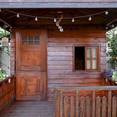 Kid's Backyard Cabin (Options: 12ft L x 8ft W, 7ft Wall H, Douglas-Fir, 4ft Front Porch Size [Included in the Overall Length], Interior Decking, Transparent Premium Sealant). Photo shows structure recently resealed after 6 years of loving service.