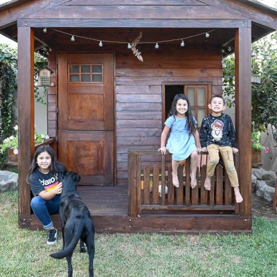 Kid's Backyard Cabin (Options: 12ft L x 8ft W, 7ft Wall H, Douglas-Fir, 4ft Front Porch Size [Included in the Overall Length], Interior Decking, Transparent Premium Sealant). Photo shows structure recently resealed after 6 years of loving service.