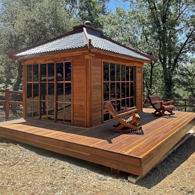 Custom Kikue's Tea House (Options: 14' x 12', 8' Wall Height, Metal Roof [Slate Gray, Metal Tile - Stile Style by bestbuymetals.com], California Redwood, with Solid Walls by Custom Request, Interior and External Decking, 6' Deck on the Front Side and 3' Decks on the Sides, Transparent Premium Sealant). Photo Also Shows 2 Ensenada Rocking Chairs. Photo Courtesy of A. Hagadron of Rough Ready, CA.