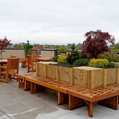Custom Square Lighthouse Garden Bench (Options: 11 1/2 ft x 14 ft with an Opening in the Center for Planter, 21 1/4 inches W x 18 inches H, California Redwood, No Cushion, No Engraving, Transparent Premium Sealant). Photo also shows two Square Patio table sets with Ruth Chairs, and some Mendocino Planters. Photo Courtesy of A. Guttman of Brooklyn, NY.