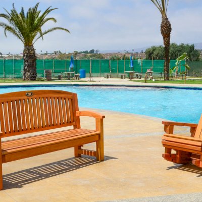 Luna Wood Memorial Bench (Options: 5 ft, Douglas-fir, No Cushion, No Engraving, Custom Plaque Provided by Customer, Transparent Premium Sealant). Photo also shows an Adirondack Rocking Chair. Photo Courtesy of El Laurel Resort of Baja, Mexico. 