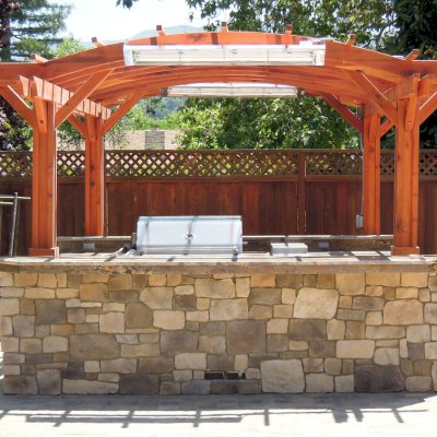 Marin Outdoor Kitchen Pergola (Options: 14' L x 16' Arc W, California Redwood, Unattached, 2 Post Electrical Wiring Trim, Arched Roof without Lattice Panels, 4-Post Anchor Kit for Stone, No Ceiling Fan Base, No Privacy, No Curtain Rods, 9 ft Post Height (front posts wrapped with masonry), Transparent Premium Sealant). 
