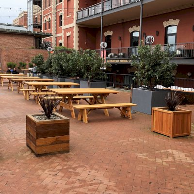 Mendocino Planters (Options: 24'' L, 24'' W, 24'' H, California Redwood, With 1 3/4-inch Feet, No Trellis, Interior and Exterior of Box with Sealant (No Growing Vegetables), Transparent Premium Sealant). Photo also shows some Forever Picnic Tables and some Napa Platers. Horizontal board planters (Mendocino Planters) were initially installed in 2015 and this is why the finish is a bit darker than the Napa Planters. Photo Courtesy of D. Harty of San Francisco, CA.