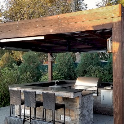 Modern Louvered Garden Pergola (Options: 18' L x 18' W, 8'' x 8'' Posts, Mobile Louvers, California Redwood, 10 ft H, 1 Electrical Wiring Trim, No Curtain Rods, 4 Post Anchor Kit for Concrete, No Post Decorative Trims, 1 Ceiling Fan Base, Coffee-Stain Premium Sealant). Photo shows faded finish - installation was completed 2 years prior. Photo Courtesy of C. Passmore of Lawrence, New York.