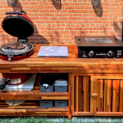Custom Outdoor Table With Built In Grill (Options: 8' L, 32" W, Mosaic Redwood, Two Shelves, Slightly Rounded Corners, 34"H, 22-inch Grill Opening, Extra Opening for Griddle, Right Side Enclosed and One Door Added by Custom Request, Transparent Premium Sealant). Legs aligned to tabletop by custom request. Photo Courtesy of S. McCord of 