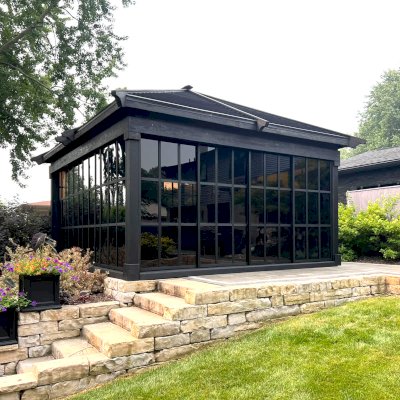 Sun Gazebo with Sliding Doors (Options: Custom Size 18' L x 15' W, Douglas-Fir, 8 ft Wall Height, 3 Sliding Walls and One Fixed Wood Wall, Without Skylight, Complete Floor, 1 Ceiling Fan Base, 1 TV Mount, Shiplap Roof, Black Stain Premium Sealant). Photo Courtesy of W. Geisert of Troy, MI.