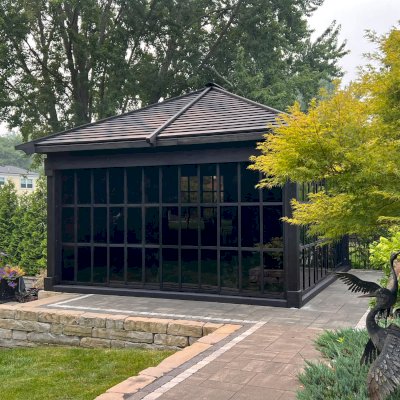 Sun Gazebo with Sliding Doors (Options: Custom Size 18' L x 15' W, Douglas-Fir, 8 ft Wall Height, 3 Sliding Walls and One Fixed Wood Wall, Without Skylight, Complete Floor, 1 Ceiling Fan Base, 1 TV Mount, Shiplap Roof, Black Stain Premium Sealant). Photo Courtesy of W. Geisert of Troy, MI.