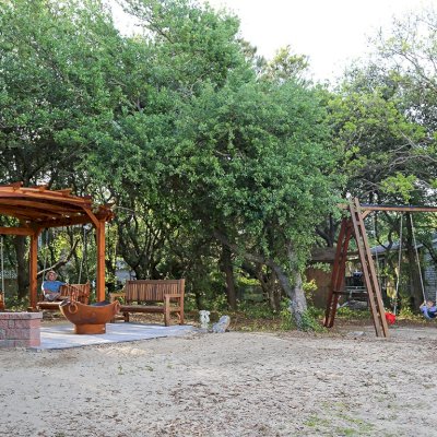 Rory's Giant Playground Swing Sets (Options: 3 Seats, Redwood, Standard Swing Seats, Transparent Premium Sealant). Photo Also Shows an Arched Pergola with Swing Benches and a Ti Amo Bench. Photo Courtesy of Tom Marten of Kitty Hawk, NC.