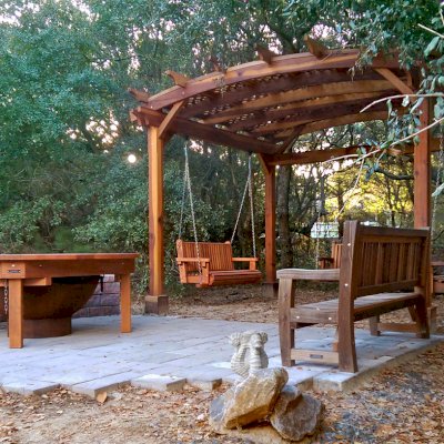 Round Outdoor Patio Table (Options: 6.5 ft, No Seating, Redwood, Standard Tabletop, No Lazy Susan, No Umbrella Hole, Transparent Premium Sealant, Braces Underneath Tabletop by Custom Request). Photo Also Shows an Arched Pergola with 3 Bench Swings and a Ti Amo Bench. Photo Courtesy of Tom Marten of Kitty Hawk, NC.
