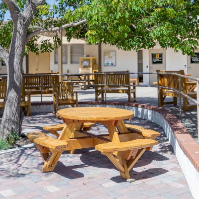 Round Wooden Picnic Table (Attached Benches) (Options: 4' Diameter, Attached Benches, Mosaic Douglas-Fir, Standard Tabletop, No Lazy Susan, No Umbrella Hole, Transparent Premium Sealant). Photo courtesy of Vanguard University [55 Fair Dr, Costa Mesa, CA].