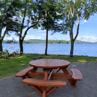 Round Wooden Picnic Tables (Attached Benches) (Options: 4.5' Diameter, Attached Benches, California Redwood, Standard Tabletop, No Lazy Susan, No Umbrella Hole, Transparent Premium Sealant). Photo Courtesy of Debbie Awalt of Alton Bay, New Hampshire.