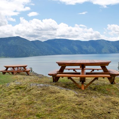 Round Wooden Picnic Tables (Attached Benches) (Options: 6' Diameter, Attached Benches, California Redwood, Standard Tabletop, No Lazy Susan, Umbrella Hole & Plug, Transparent Premium Sealant). These beautiful tables are installed at the “Bull Pine Ledge”, looking out on Lake Pend Orielle from Cloudsledge Conservation Trust, Hope Idaho. Photo Courtesy of Art Green.