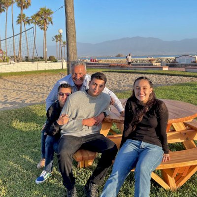 Round Wooden Picnic Table (Attached Benches) (Options: 5' Diameter, Attached Benches, Mosaic Douglas-Fir, Standard Tabletop, No Lazy Susan, 2" Umbrella Hole, Transparent Premium Sealant). Photo courtesy of El Estero Beach Resort in Ensenada, Mexico.