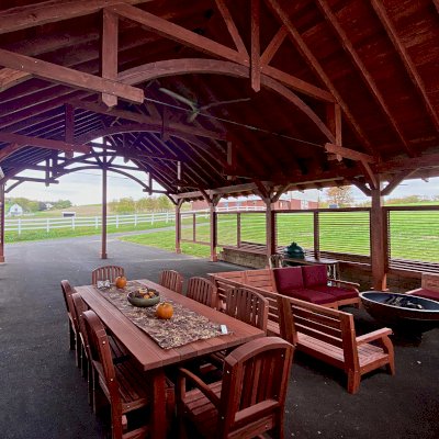 San Francisco Redwood Patio Table Under a Cardinal's Nest Pavilion (Options: 8' L, 48" W Tabletop, 2 Armchairs + Side Chairs, Douglas-fir, Luna Chairs, Standard Tabletop, Slightly Rounded Corners, No Umbrella Hole, Cherry Stain Premium Sealant). Photo Also Shows Some Custom Kari's Chairs and a Cardinal's Nest Pavilion. Photo Courtesy of S. Steckman of East Liverpool, Ohio.