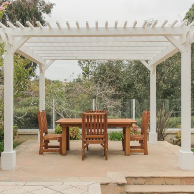 San Francisco Redwood Patio Table (Options: 6' L, 40 1/4" W Tabletop, Chairs, Mature Redwood, 4 Chairs, Ruth Chair Design, All Side Chairs, No Cushions, Old Country Tabletop, Standard, Squared Corners, No Umbrella Hole, Transparent Premium Sealant). Table Set Under a Traditional Garden Pergola in White Finish. Photo Courtesy of J. Schulte of Laguna Niguel, CA.