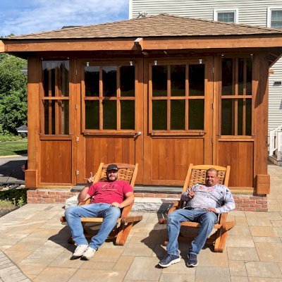 Spa Gazebo Kit (Options: 20' L, 14' W, Mature Redwood, All Sliding Windows, Without Skylight, Custom Roof, 36" H Siding Below Windows, Vertical Siding, Custom French Door without Screens, No Flooring, Transparent Premium Sealant). Photo Also Shows 2 Rio Hammock Chairs. Photo Courtesy of J. Zawalski of Groveland, Massachusetts.