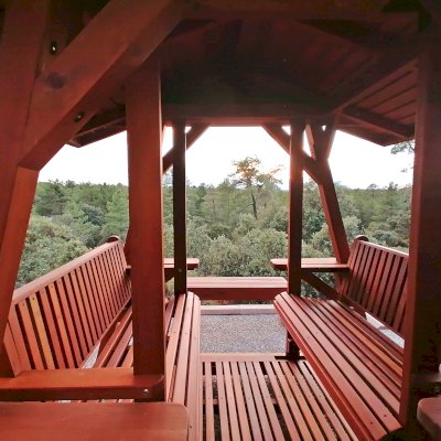 St. Anthony's Face to Face Gliders (Extra Wide, Mature Redwood, With Beverage Armrests, With Kid's Platform, Extra Wide Roof, No Engraving, Transparent Premium Sealant). Photo Taken 4 Years After Installation. Photo Courtesy of P. Molina of Marugan, Segovia.