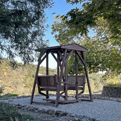 St. Anthony's Face to Face Glider (Adult Size, Mosaic Redwood, Standard Closed Roof, No Beverage Armrests, No Platform, No Engraving, Transparent Premium Sealant). Photo Taken 3 Years After Installation. Photo Courtesy of S. Moore of Shingle Springs, CA.
