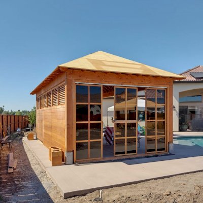 Custom Sun Gazebo with Sliding Doors (Options: 24' L x 16' W, Douglas-fir, with 1 Custom Solid Wall, 1 Side with Sliding Doors and 2 Open Sides, 9 ft Wall Height, Without Skylight, No Floor, Custom Roof, Transparent Premium Sealant). Photo Taken During Installation. Photo Courtesy of J. Reid of Chico, California.