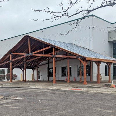Esther Scissor Truss Pavilion (Options: 33’ L x 63’ W, California Redwood, Standard 3/4" T&G Roof Boards, 16' and 10' H Posts by Custom Request, with 4 Ceiling Fan Bases, High-Wind Post Anchors, 5:12 Roof Pitch, Transparent Premium Sealant). Installation in Process, Photo Shows the Final Roofing Only Partially Installed. Photo Courtesy of the HelloFresh Produce Company of Bolingbrook, IL.