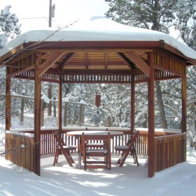 Hexagonal Retreat Pavilion (Options: 14' Diameter, No Deck, California Redwood, With Upper and Lower Panels, Transparent Premium Sealant).  Round Folding Table Set with Chairs Under Pavilion. Photo Courtesy of Ms. Karen McCartney of Tijeras, NM.  