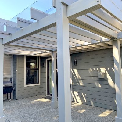 Custom L.A. Modern Pergola (Options: 17' L, 12' W, Douglas-fir, 10.5 ft Post Height, No Electrical Wiring Trim Kit, 4-Post Anchor Kit for Concrete, No Ceiling Fan Base,  with Transparent Rain Guard, Custom Paint Finish) with 1 Standalone Privacy Panel (Louvered). Photo Courtesy of J. Williamson of Bow, Washington.
