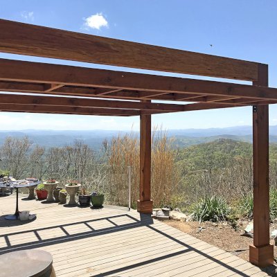 Custom L.A. Modern Pergola (Options: 16' L, 13' W, California Redwood, No Rain Guard, 12" x 4" Posts & Supports,  10 ft Post Height, No Electrical Wiring Trim, 4-Post Anchor Kit for High-Wind, No Ceiling Fan Base, Retractable Shade Canopy will be Installed, Transparent Premium Sealant). Photo Courtesy of W. Craig of Fairview, North Carolina. Blue Ridge Mountains in the background.