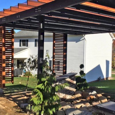 Custom L.A. Modern Pergola (Options: 42' L, 20' W, California Redwood, 10 ft Post Height, Electrical Wiring Trim for 1 Post, 8-Post Anchor Kit for Concrete, 1 Ceiling Fan Base, Rain Guard [3/16" Polycarbonate], Transparent Premium Sealant for Louvers & Rafters and Black Stain for Posts & Supports). Photo Courtesy of L &M Oliverio of Bridgeport, West Virginia.