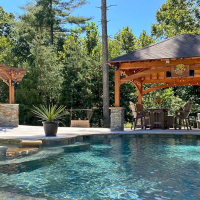 Loreto Pavilion (Options: 20' L x 20' W, 8x8 Posts, No Privacy Panels, Douglas-fir, 9.5' H, Electrical Wiring for 1 Post, 4-Post Anchor Kit for High Wind, No Post Decorative Trim, 1 Ceiling Fan Base, No Curtain Rods, Transparent Premium Sealant). Photo Also Shows a Marin Pergola. Photo Courtesy of Bill & Lori O’Mara of Marion, North Carolina.