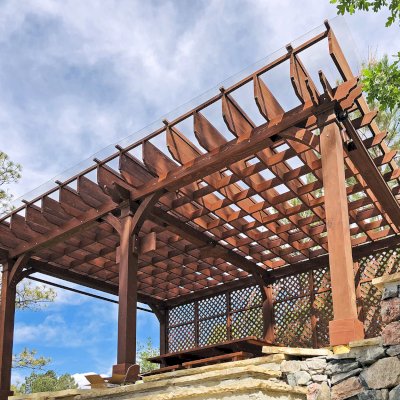 Montvale Pergolas (Options: 24' x 16', Mature Redwood, 6-Post Anchor Kit for Concrete, 1 Ceiling Fan Base and 1 T.V. Base, 2 Curtain Rods, 1 Lattice Privacy Panel, 9.5' H Posts, with Rain Guard, Coffee-Stain Premium Sealant). A Forever Picnic Table Set with Unattached Benches Shown Under the Pergola. Photo Courtesy of J. Brinkman of Castle Rock, Colorado.