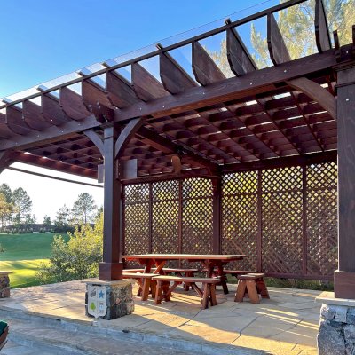 Montvale Pergolas (Options: 24' x 16', Mature Redwood, 6-Post Anchor Kit for Concrete, 1 Ceiling Fan Base and 1 T.V. Base, 2 Curtain Rods, 1 Lattice Privacy Panel, 9.5' H Posts, with Rain Guard, Coffee-Stain Premium Sealant). Photo Also Shows Some Adirondack Chairs with Ottoman. Photo Taken 1 Year After Installation, and After Restaining. Photo Courtesy of J. Brinkman of Castle Rock, Colorado.