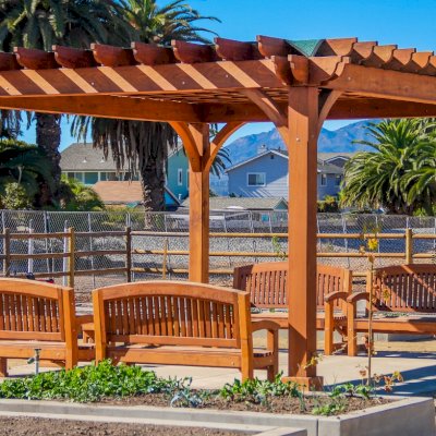 Montvale Pergolas (Options: 16' x 20', Mature Redwood, 4-Post Anchor Kit for Concrete, No Ceiling Fan Base, No Curtain Rods, No Privacy Panels, 9.5' Post, Transparent Premium Sealant). Photo also shows some Luna Memorial Benches and Lighthouse Benches. Sunbrella shade fabric above the pergola was ordered from: www.patiolane.com as a custom item. Photo Courtesy of Carpinteria Park, 5775 Carpinteria Avenue  Carpinteria, CA  93013.