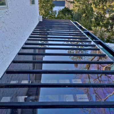 Custom Attached Silverado Modern Pergola (Options: 36' L, 10' W, Cantilevered Roof Style, 12" Roof Rafter Spacing, California Redwood, 2 Ceiling Fan Bases, 4-Post Anchor kit for Concrete, Black Stain Premium Sealant). Photo Courtesy of A. Papantomiou of Manhasset, New York.
