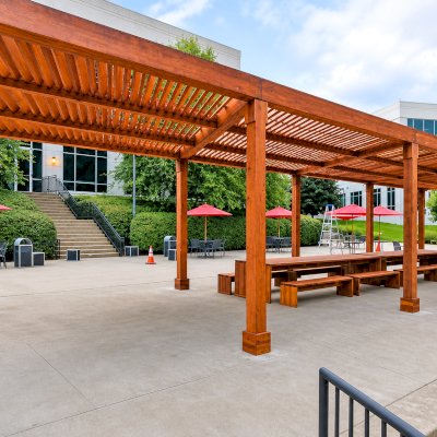Silverado Modern Pergola (Options: 58' L, 16' W, Standard Roof Style, California Redwood, No Electrical Wiring Trim, with 1 3/4" x 11 1/4" Roof Support Timbers and 7 1/4" x 7 1/4" Posts, Post Anchor Kit for Concrete, No Privacy Panels, No Curtain Rods, 10' Post Height, Transparent Premium Sealant). Photo Also Shows 2 Maynard Modern Redwood Patio Table Sets Under the Pergola. Photo Courtesy of A. Arena of Morristown, New Jersey.