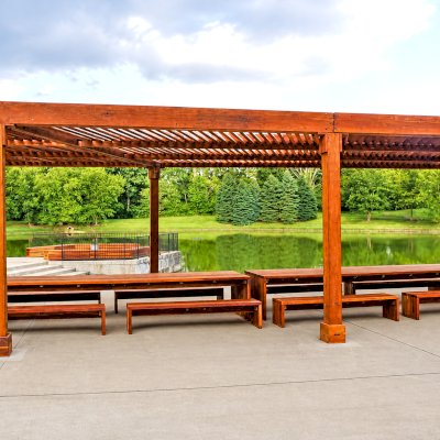 Silverado Modern Pergola (Options: 58' L, 16' W, Standard Roof Style, California Redwood, No Electrical Wiring Trim, with 1 3/4" x 11 1/4" Roof Support Timbers and 7 1/4" x 7 1/4" Posts, Post Anchor Kit for Concrete, No Privacy Panels, No Curtain Rods, 10' Post Height, Transparent Premium Sealant). Photo Also Shows 2 Maynard Modern Redwood Patio Table Sets Under the Pergola. Photo Courtesy of A. Arena of Morristown, New Jersey.