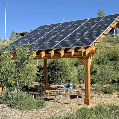 Solar Pergola (Options: 23' L x 18' W, Mosaic California Redwood, 12:7 Pitch, Post Anchor Kit for High-Wind, Transparent Premium Sealant). Pergola Installed in Colorado Mountain College in Steamboat Springs, CO.