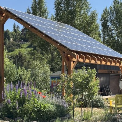 Solar Pergola (Options: 23' L x 18' W, Mosaic California Redwood, 12:7 Pitch, Post Anchor Kit for High-Wind, Transparent Premium Sealant). Pergola Installed in Colorado Mountain College in Steamboat Springs, CO.