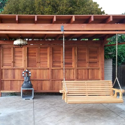 Sunset Patio Pavilion (Options: 18' x 14', 1 Shutter Privacy Panel [Top] with Solid Wall [Bottom], Mature Redwood, 9ft H, No Electrical Wiring Trim, 4-Post Anchor Kit for High-Wind, No Ceiling Fan Base, 3 Curtain Rods, Transparent Premium Sealant). The Photo Also Shows a Large Bench Swing Seat in Douglas-fir, Ensenada Seat Style.