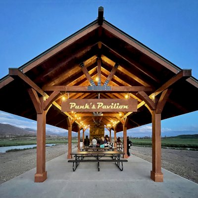 Custom Thick Timber Toledo Wood Pavilion (Options: 50' L x 24' W, Douglas-fir, 8-Post Anchor Kit for High-Wind, No Electrical Wiring Trim Kit, 10 x 8 Supports, 10 x 10 Posts & 2 x 8 Rafters, 4' Overhang by Custom Request, with 20" x 8' Cutout on the Back to Fit Fireplace, Coffee-Stain Premium Sealant). Photo Courtesy of G. Hileman of Grand Lake, Colorado.