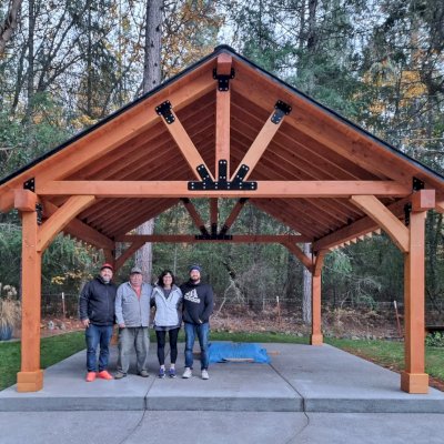 Thick Timber Toledo Wood Pavilion (Options: 20' L x 20' W, Douglas-fir, 4-Post Anchor Kit for Concrete, 8' H Posts, No Electrical Wiring Trim, 8 x 8 Posts and Trusses, 8 x 10 Supports, 2 x 8 Rafters, No Fan Bases, Transparent Premium Sealant). Photo Courtesy of B. Read of Grants Pass, Oregon.